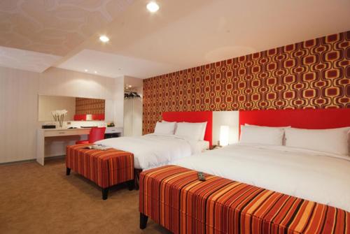 a hotel room with two beds and a red wall at Hotel Leisure 台中輕行旅 in Taichung
