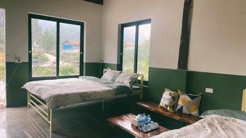 two beds in a room with green walls and windows at Stella Đồng Lâm Homestay in Làng Ben