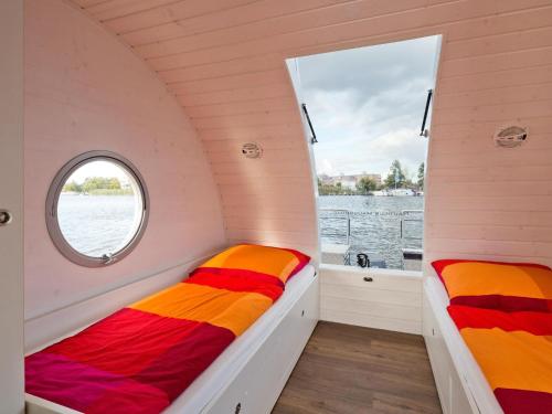 two beds in a small room with a window at Houseboat on the Dahme in Niederlehme