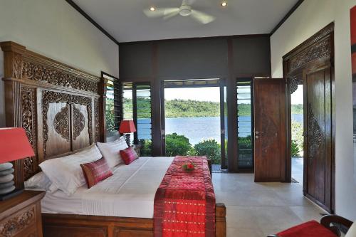 a bedroom with a large bed with a large window at Private Island Experience in Vitouara