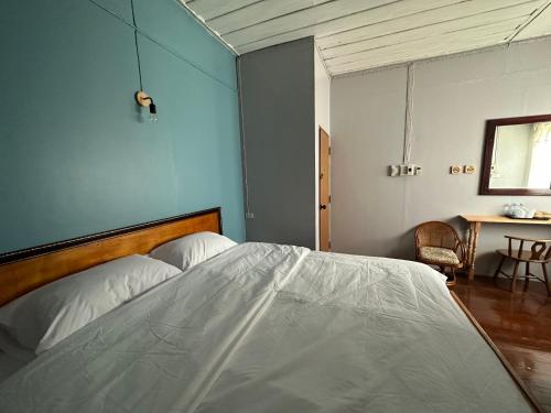 a bedroom with a white bed with a blue wall at THADAN GUEST HOUSE in Ban Houayxay