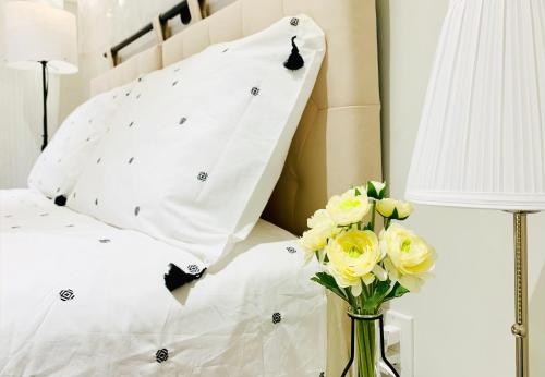 a bed with white pillows and a vase of yellow flowers at Private Studio Suite with Full Bath - Parking - 15 mins to Downtown in Vancouver