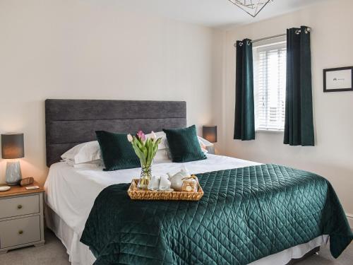 a bedroom with a green bed with a tray of flowers at The Gables in Helmsley