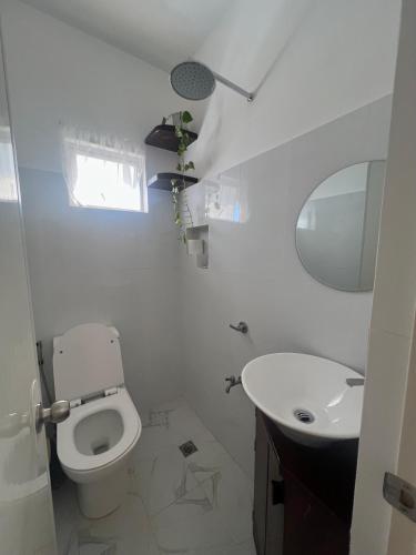 a white bathroom with a toilet and a sink at RICH-VANIA SUITES in General Luna