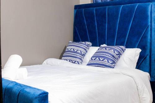 uma cama com uma cabeceira azul com almofadas em Leleshwa luxury Apartments em Nairobi