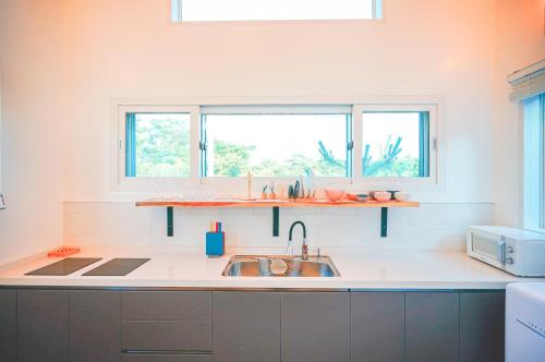 a kitchen with a sink and two windows at Jeju Love Stay Purple in Jeju