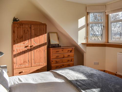 a bedroom with a bed and a dresser with a mirror at Caldhame Smiddy in Marykirk
