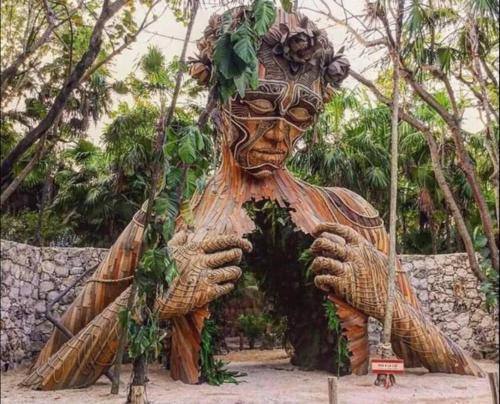 Una gran estatua de madera de una persona con hojas. en Departamento AJAL TULUM, en Tulum