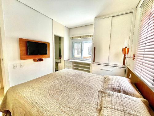 a bedroom with a bed and a flat screen tv at Cobertura com piscina e churrasqueira, 200m da praia, 3 dormitórios para até 6 hóspedes in Guarujá