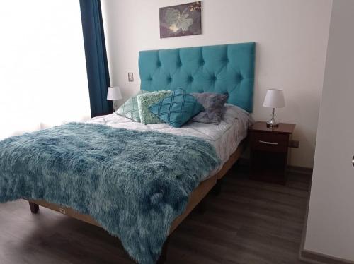 a bedroom with a large bed with a blue headboard at Open House Apart Centro Iquique in Iquique