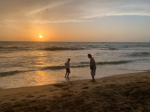 two men standing on the beach watching the sunset at MILLET'S FOOD COMPANY AND COOKING CENTER in Negombo