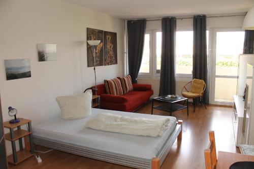 uma sala de estar com uma cama e um sofá vermelho em Ferienappartement K112 für 2-4 Personen in Strandnähe em Schönberg in Holstein