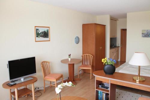 uma sala de estar com televisão e uma mesa com cadeiras em Ferienappartement K1208 mit Ostseeblick em Brasilien
