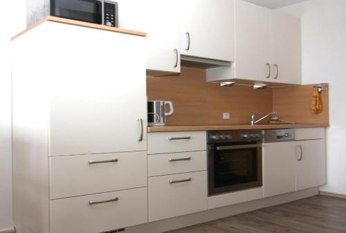 a kitchen with white cabinets and a microwave at Ferienwohnung K1414 für 2-4 Personen mit Ostseeblick in Brasilien
