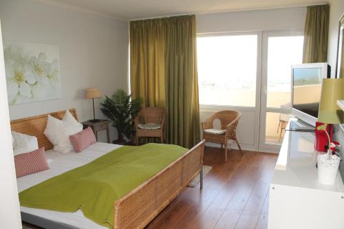 a bedroom with a bed with a green blanket on it at Ferienwohnung K1606 für 2-4 Personen mit Ostseeblick in Kalifornien