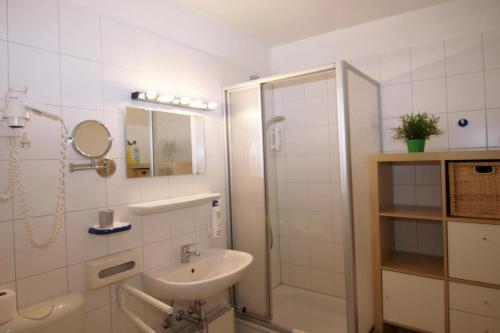 a white bathroom with a sink and a shower at Ferienwohnung K1606 für 2-4 Personen mit Ostseeblick in Kalifornien