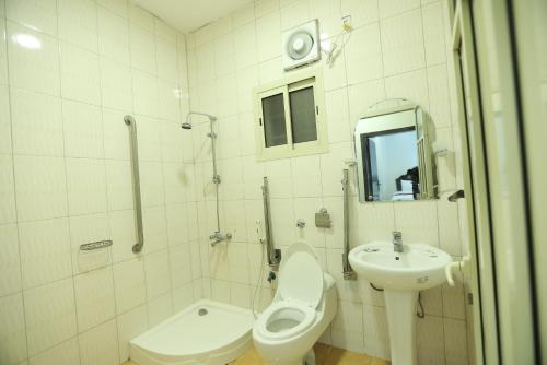 ein weißes Bad mit einem WC und einem Waschbecken in der Unterkunft العيرى للشقق المخدومه جازان 1 in Dschāzān