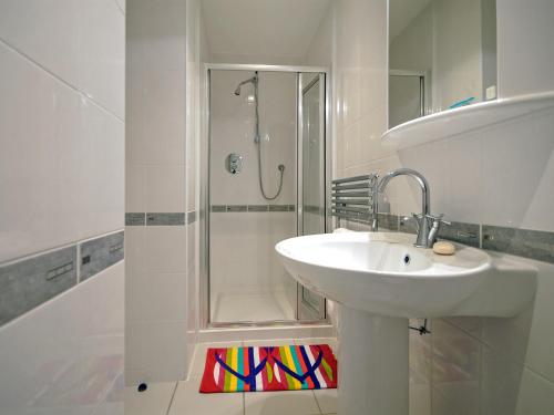 La salle de bains blanche est pourvue d'un lavabo et d'une douche. dans l'établissement Havens Rest, à Walton West