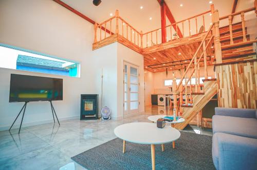 uma sala de estar com uma mesa e uma televisão e uma escada em Jeju Love Stay Mint em Jeju