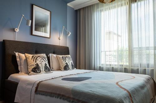 a bedroom with a large bed with blue walls and a window at Smokinia Sunrise - Kavatsi Beach, Sozopol in Sozopol