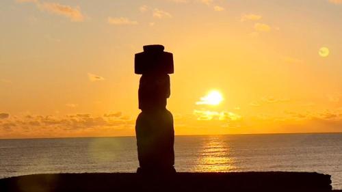 a silhouette of a person standing on the beach at sunset at Hotel Maea Hare Repa in Hanga Roa