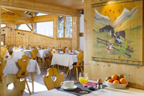 een restaurant met tafels en stoelen en een schilderij aan de muur bij L'Hermine Blanche in Morzine