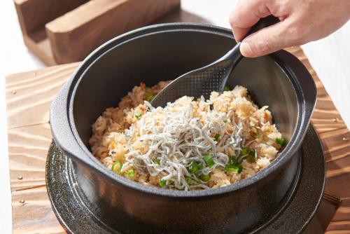 a person stirring a bowl of food with a fork at Hiroshima Tokyu REI Hotel in Hiroshima