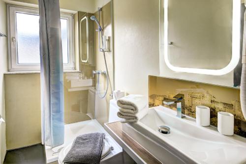 een badkamer met een wastafel, een douche en een spiegel bij Hotel Hofmann in Salzburg