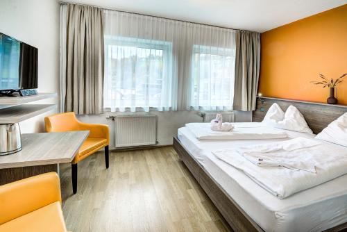 ザルツブルクにあるホテル ホフマンの大きなベッドとテーブルが備わるホテルルームです。