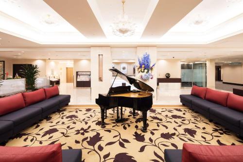 高崎的住宿－高崎大都會酒店，带沙发的客厅里的钢琴