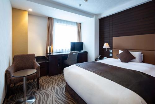 a hotel room with a large bed and a desk at Hotel Metropolitan Takasaki in Takasaki