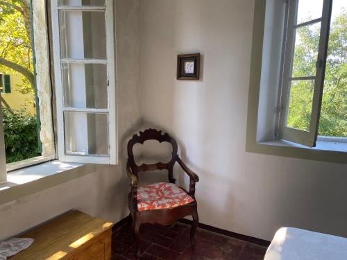 a chair sitting in the corner of a room with two windows at B&B Ostria Vento in Medesano