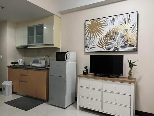 a kitchen with a refrigerator and a tv on the wall at F&M Relaxing Hotel in Manila