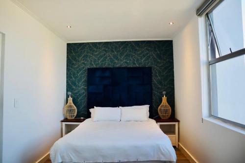 1 dormitorio con 1 cama grande y pared azul en Stay Ulo at The Apex on Smuts, en Johannesburgo