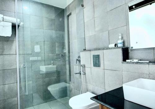 a bathroom with a shower and a toilet and a sink at The Cloyster Resort and Spa in Rāmnagar