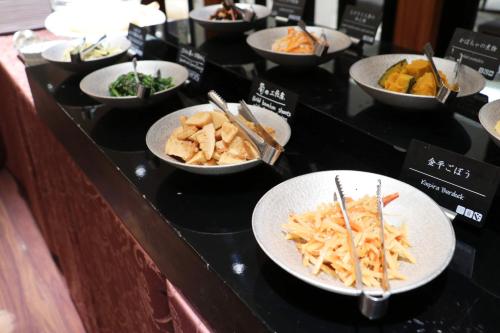 a buffet with bowls of food on a counter at Hotel Metropolitan Takasaki in Takasaki