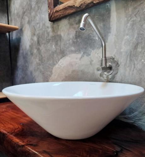 a white bowl sink on a wooden counter in a bathroom at Pencave Homestay in Pang Mapha