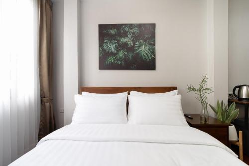 a bedroom with a white bed with white pillows at Homie Non - โฮมมี่ นนท์ in Ban Bang Khwang