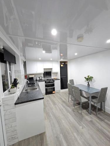 a large white kitchen with a table and chairs at Cheerful Home near Preston train station & Uclan in Preston