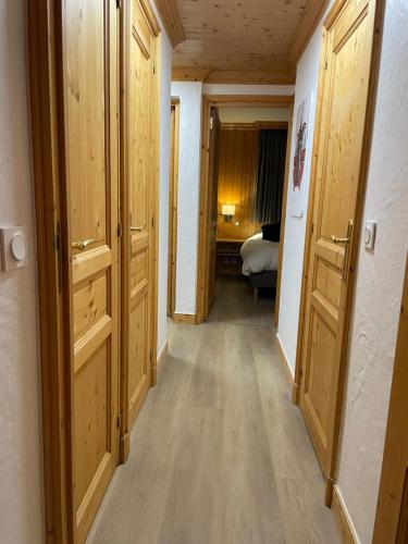 a hallway with wooden doors and a room with a bed at Meribel Centre La Chaudanne, real ski in and out, 3 bedrooms 2 bathrooms newly renovated, Chalet l'Épervière in Méribel