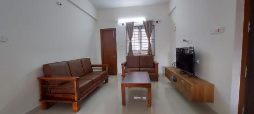 a living room with a couch and a chair and a tv at Tranquil Serviced Apartments - Sarjapur in Bengaluru