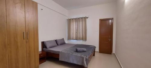 a small bedroom with a bed and a window at Tranquil Serviced Apartments - Sarjapur in Bengaluru