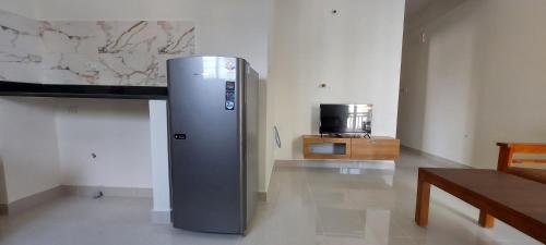 a refrigerator in a room with a table and a tv at Tranquil Serviced Apartments - Sarjapur in Bengaluru
