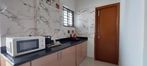 a kitchen with a microwave and a tv on a counter at Tranquil Serviced Apartments - Sarjapur in Bengaluru