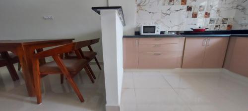 a kitchen with a table and chairs and a microwave at Tranquil Serviced Apartments - Sarjapur in Bengaluru