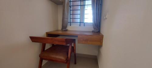 a wooden desk with a chair and a window at Tranquil Serviced Apartments - Sarjapur in Bengaluru