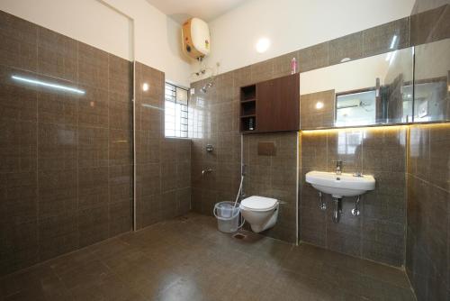a bathroom with a toilet and a sink and a shower at Aayushman Luxury Homes in Sarjāpur