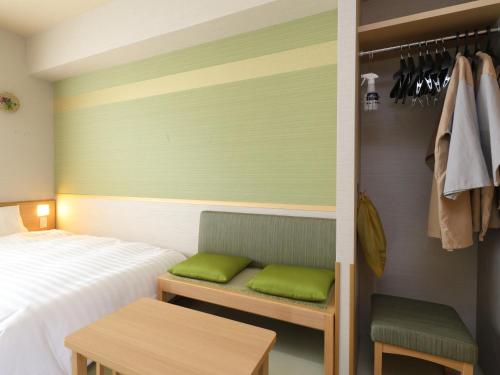 1 dormitorio con 1 cama y un banco con almohadas verdes en Beppu Hatto Onyado Nono Beppu en Beppu