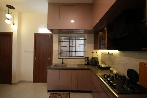 a kitchen with brown cabinets and a sink and a stove at Aayushman Luxury Homes in Sarjāpur