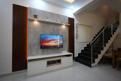 a living room with a flat screen tv on a wall at Aayushman Luxury Homes in Sarjāpur